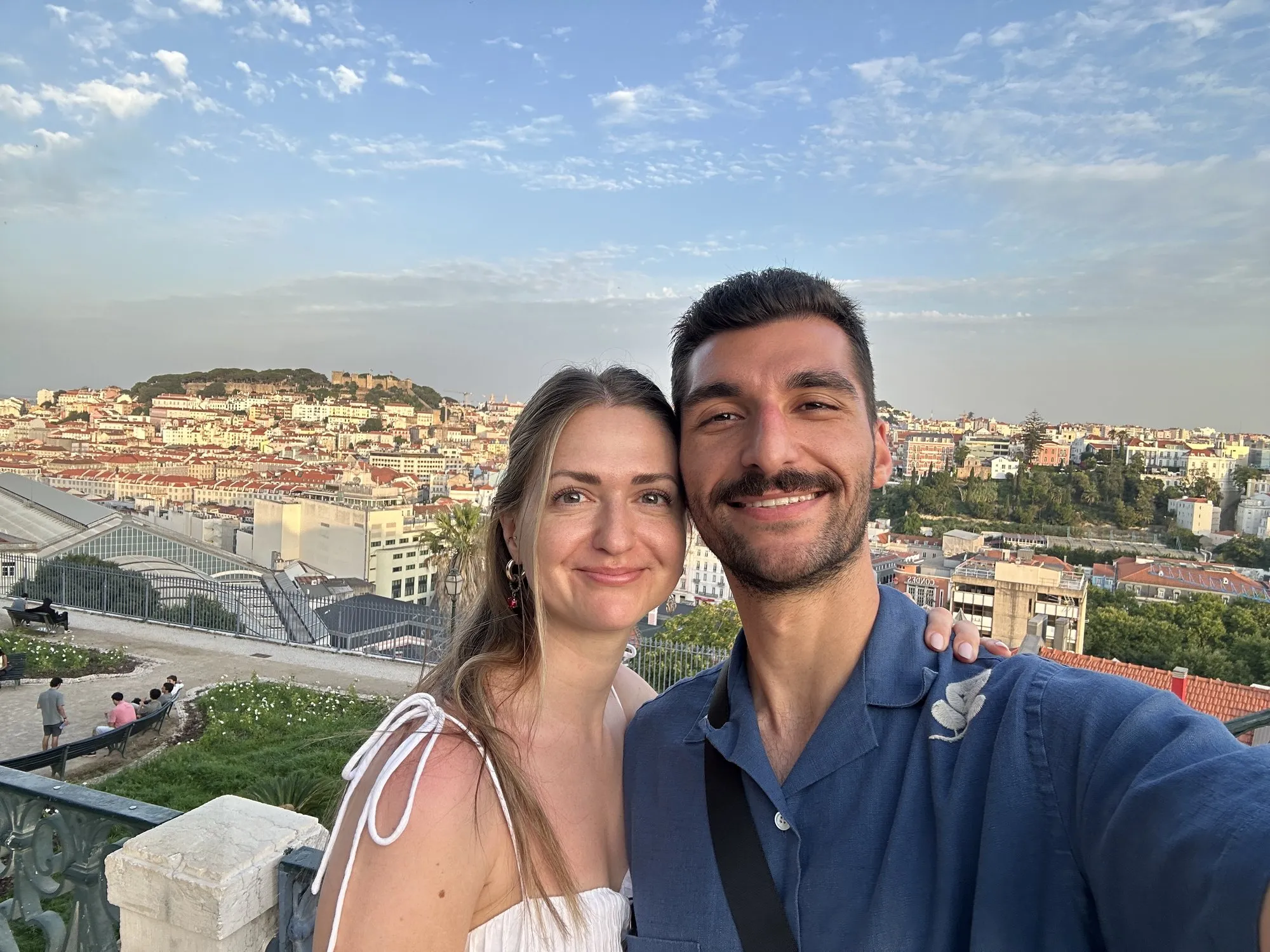 Alex and a friend taking a selfie above a city at sunset
